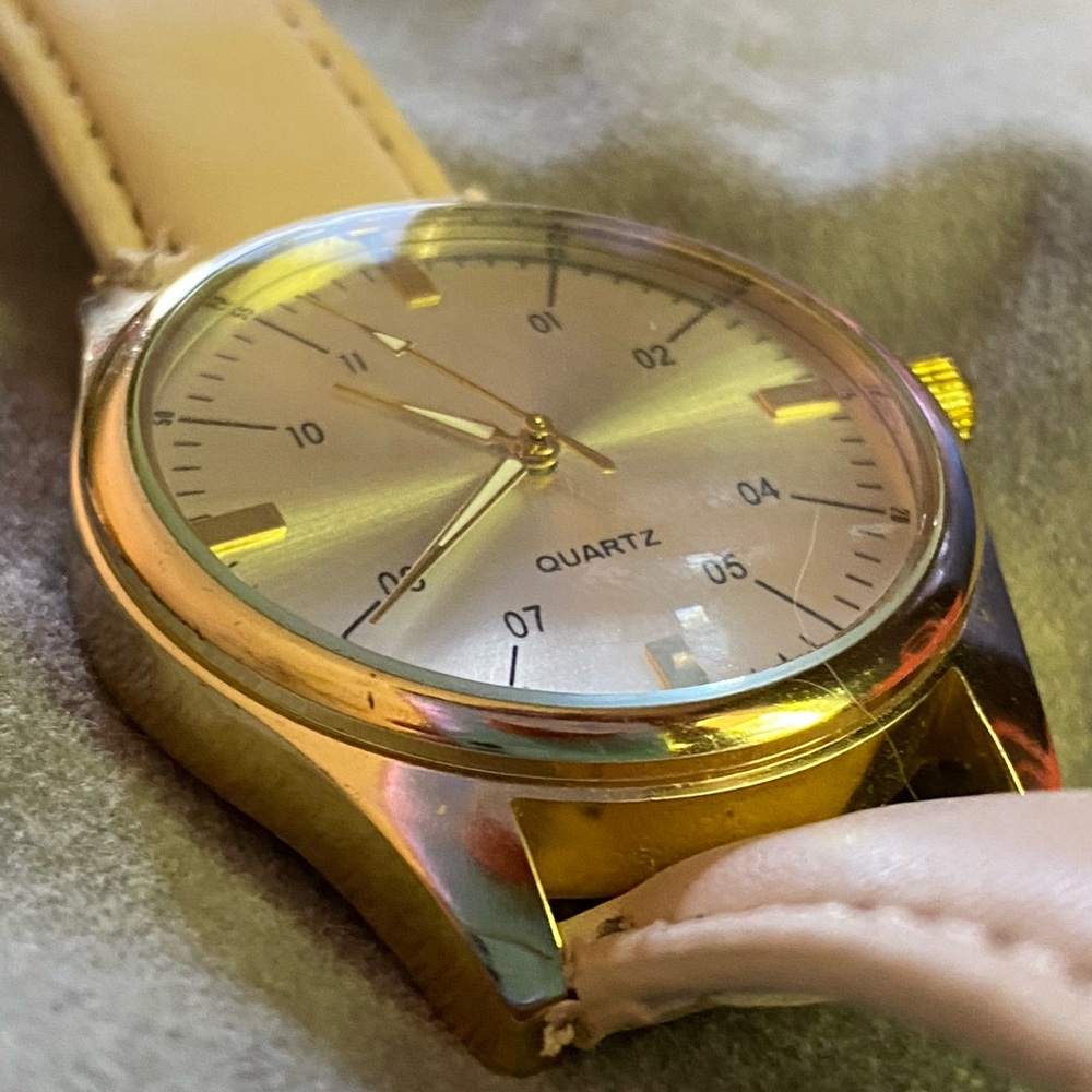 Ladies fashion gold tone watch with quartz face, and a cream faux leather band.